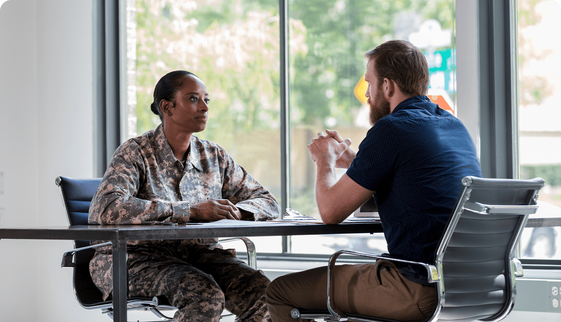 Man and woman sitting at a table in an office, engaged in conversation