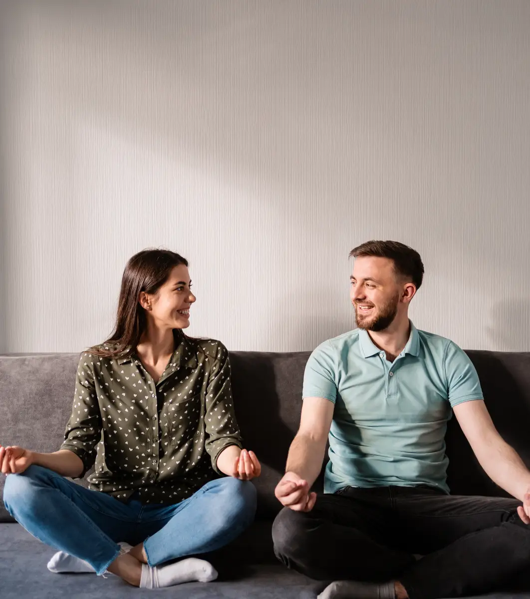 Man and woman sitting on a couch, meditating together